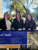 Three women standing behind a sign