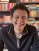 A photo of Ben Fong Smiling at the camera infront of books