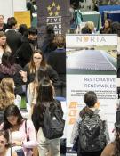  Many students crowd around employers and their banners at a career fair