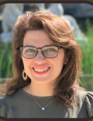 a photo of Leyla Tajir, a woman with long brown hair and glasses.