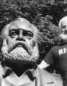 a black and white photo of a man standing next to a statue.