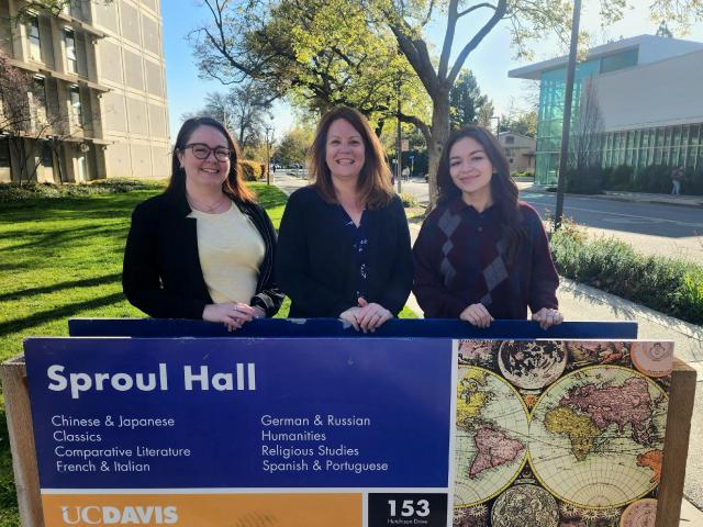 Three women standing behind a sign