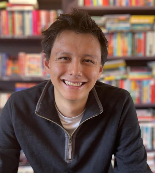A photo of a man (Ben Fong) in front of a bookshelf, smiling at the camera