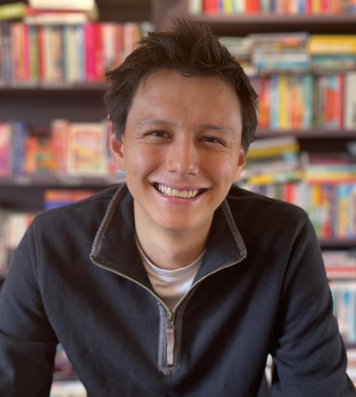 A photo of a man (Ben Fong) in front of a bookshelf, smiling at the camera