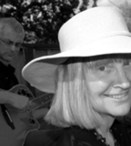 Woman in a hat with guitarist in the background