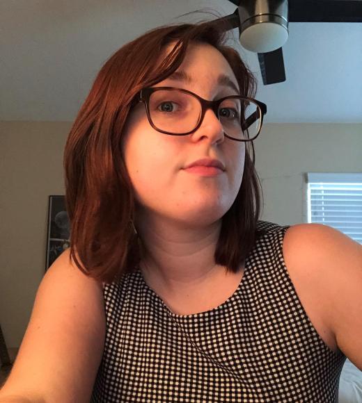 A woman wearing glasses looks at the camera