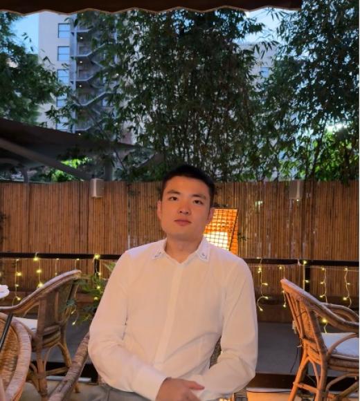 Man sitting in white oxford shirt with a wooden fence in the background