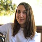 A woman with long brown hair wearing a white shirt