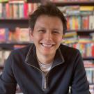 A photo of a man (Ben Fong) in front of a bookshelf, smiling at the camera