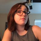 A woman wearing glasses looks at the camera