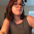 A woman wearing glasses looks at the camera