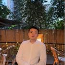 Man sitting in white oxford shirt with a wooden fence in the background