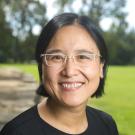 Woman in glasses standing in front of a grassy field
